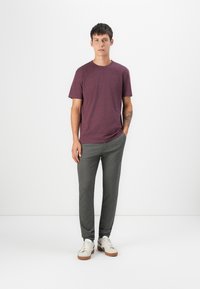 Camiseta roja de manga corta, pantalones gris ajustados y zapatillas blancas con acentos marrones. Diseño simple con un ajuste relajado y una textura suave.