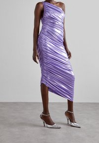 Fialové šaty na jedno rameno s řasením, vyrobené z lesklé látky; asymetrický lem; zkombinované se stříbrnými lodičkami na vysokém podpatku s pásky kolem kotníků.