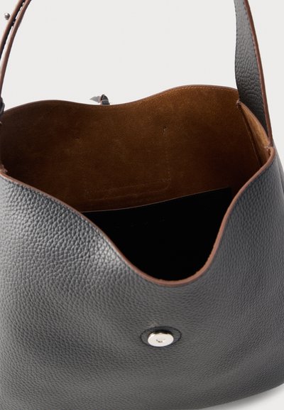 Μαύρη υφασμάτινη δερμάτινη τσάντα ώμου με ανοιχτή κορυφή που αποκαλύπτει καφέ σουέντ εσωτερικό και ασημένιο μαγνητικό κούμπωμα στο μπροστινό μέρος.