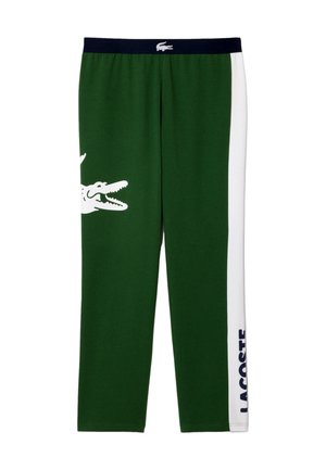 Gröna bomullsbyxor med vita sidostreck, med en stor krokodilgrafik och "LACOSTE"-text i blått på underbenet. Elastisk midja.