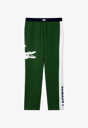Pantaloni jogger verzi din bumbac, cu dungi laterale albe, având un grafic mare cu un crocodil și textul "LACOSTE" în albastru pe piciorul inferior. Talie elastică.