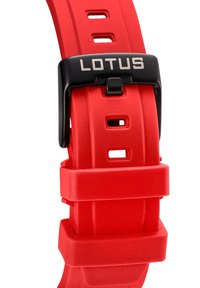 Červený silikónový remienok na hodinky s čiernou prackou. Obsahuje nastaviteľné otvory na zapínanie a vyrazené logo "LOTUS" na pracke. Hladký povrch.