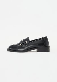 Schwarze Lederloafer mit niedrigem Blockabsatz, runder Schuhspitze und goldfarbener Schnallenverzierung auf dem Blatt. Glatte Textur, klassisches Design.