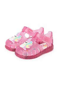 Pink glittery sandals with a closed toe, strap closure, and unicorn designs on the front. Made of translucent, flexible material.