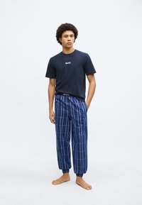 Tricou bleumarin din bumbac cu logo-ul "BOSS", asortat cu pantaloni de pijama în carouri alb-albastre, cu mansete și talie elastice.