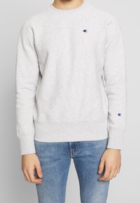Grauer Sweatshirt mit Rundhalsausschnitt, elastischen Bündchen und Saum, mit einem kleinen gestickten Logo auf der linken Brust und dem linken Ärmel.