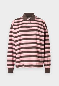 Μπλούζα ράγκμπι με μακριά μανίκια, ροζ και καφέ οριζόντιες ρίγες, καφέ γιακά και μανσέτες, δύο λευκά κουμπιά και μικρό λευκό λογότυπο της μάρκας στο στήθος.