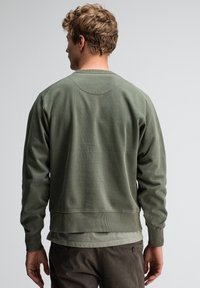 Olijfgroen sweatshirt met een ronde hals, ribgebreide manchetten en zoom, gemaakt van zacht materiaal; heeft een eenvoudige, gladde textuur.