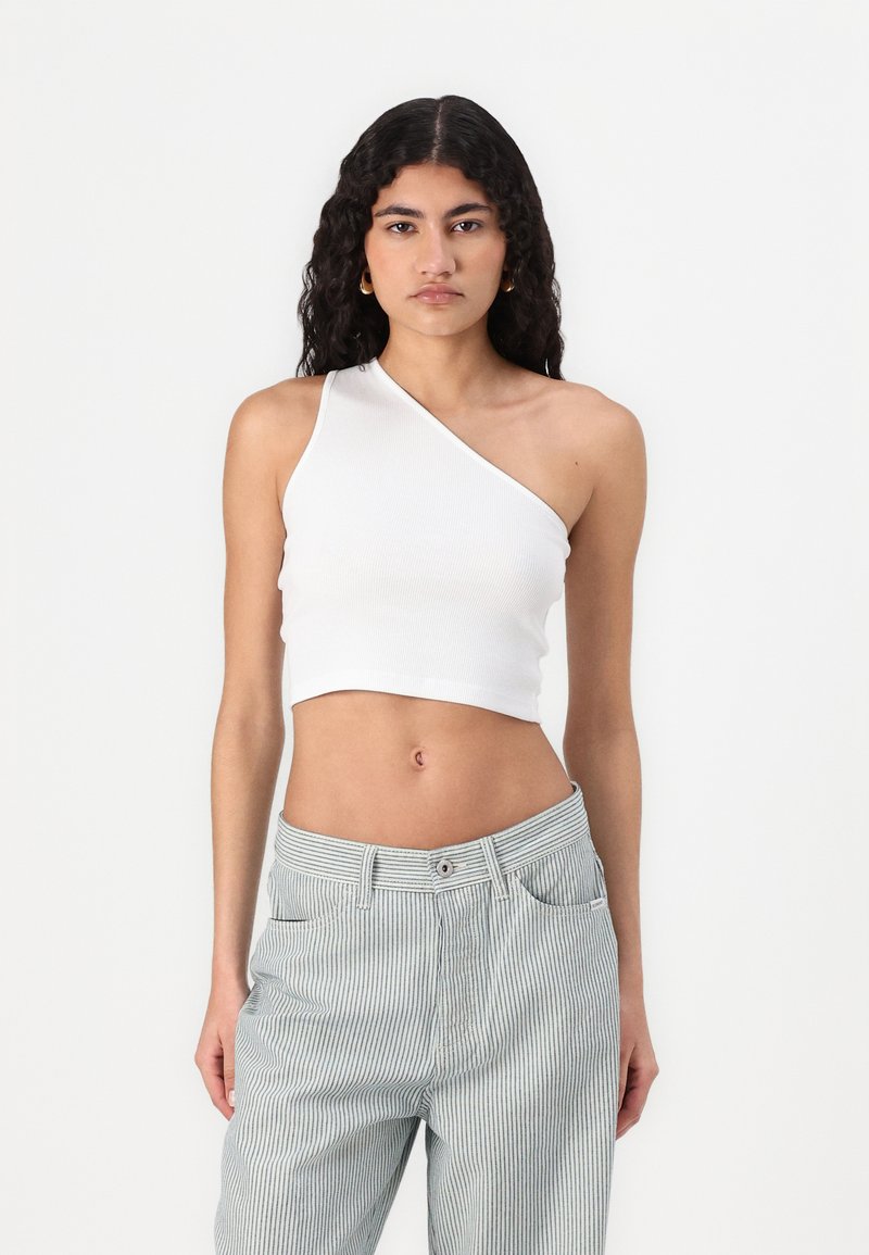 Asymmetrische witte cropped tanktop met ribbelstructuur, gecombineerd met lichtgrijze gestreepte hoge taille broeken met zijzakken en een knoopsluiting.
