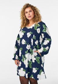 Marineblaues Blumenkleid mit großen weißen Blumen und grünen Blättern, langen Ärmeln, V-Ausschnitt und seitlichen Taschen, aus leichtem Stoff gefertigt.