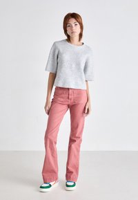 Light grey ribbed short-sleeve sweater paired with high-waisted pink jeans and multicolored platform sneakers. Minimalist design with clean lines.