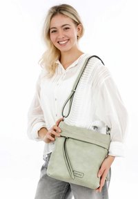 Borsa a tracolla in ecopelle verde con tracolla regolabile, chiusura con zip e dettagli frontali. Texture morbida con un design minimalista.
