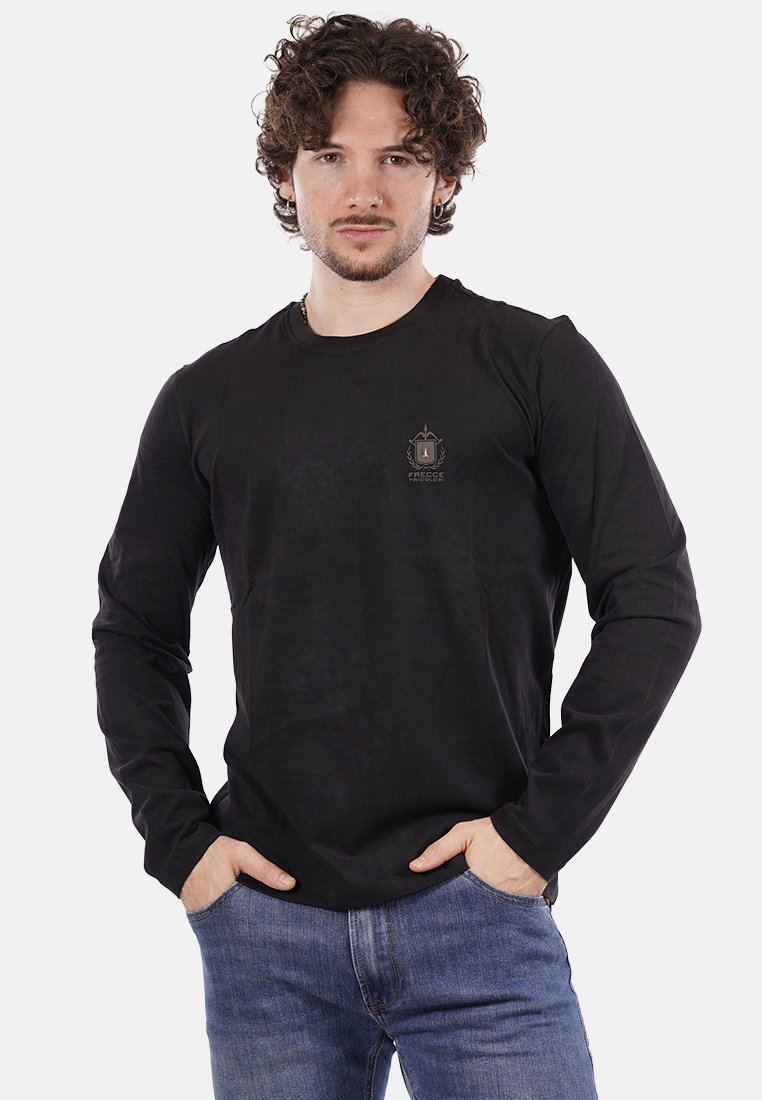 Maglietta nera a maniche lunghe realizzata in tessuto liscio, con un piccolo logo sul petto. Abbinata a jeans di denim azzurro chiaro.