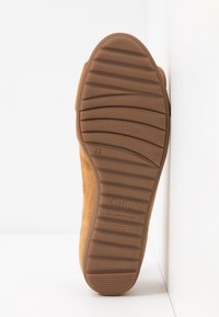 Semelle de chaussure marron avec des motifs de grip horizontaux, marquée "Gabor" et "air cube,", présentée sur fond blanc.