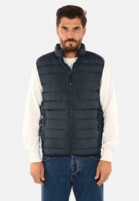 Gilet imbottito blu scuro con colletto alto, zip frontale a tutta lunghezza e due tasche laterali. Presenta un motivo a righe verticali e materiale leggero.