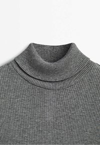 Col roulé côtelé gris en maille tricotée couvrant le col et le haut de la poitrine, montrant la texture douce du tissu et les fines côtes verticales.