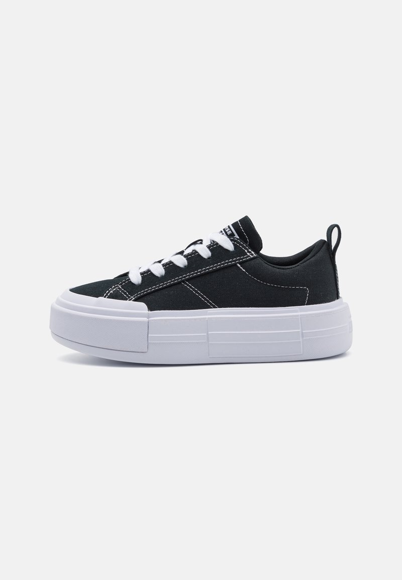 Sorte kanvas-sneakers med hvite lisser, en kraftig hvit såle og kontraststing. Har en drahank på hælen for enkel påkledning.
