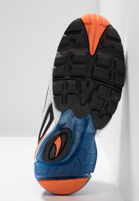 Semelle de chaussure de course noire et orange avec une surface en caoutchouc texturé, une section de rembourrage bleue et un motif de semelle prononcé pour l'adhérence.
