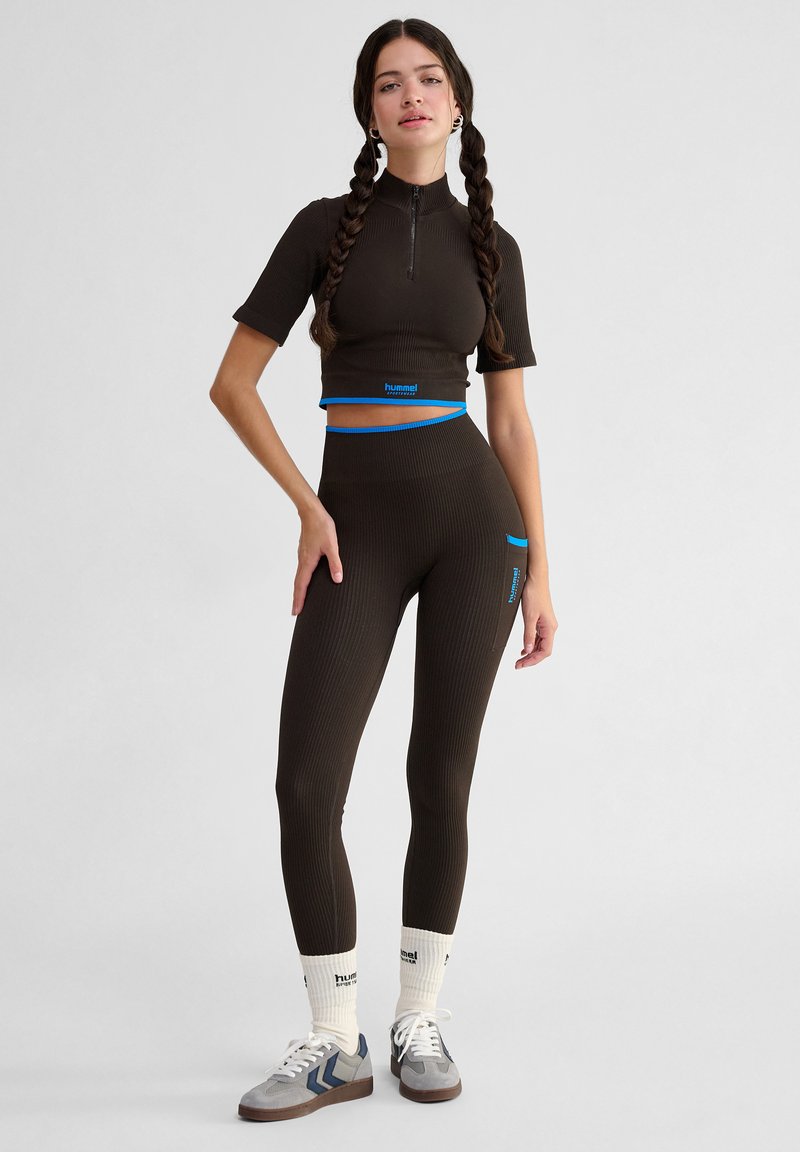 Bruine geribbelde crop top met korte mouwen en een hoge hals, gecombineerd met bijpassende high-waisted legging met blauwe accenten.
