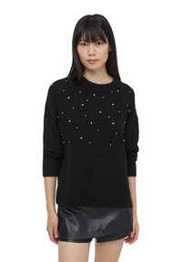 Maglione nero a maglia con maniche corte, caratterizzato da perline bianche sparse sul davanti. Texture morbida, scollatura rotonda, vestibilità rilassata.