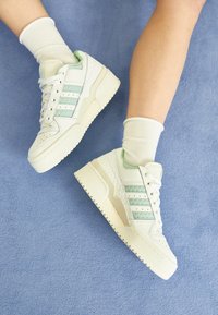 Höga sneakers i vitt och mintgrönt läder, med perforerad tå, meshdetaljer och texturerad sula. Bärs med vita ankelsockar.