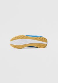 Suela de zapatilla deportiva azul con un patrón de banda de rodadura de goma texturizada, que presenta una entresuela blanca y una suela exterior de goma para una mejor tracción.
