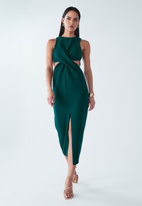 Obleka v modrozelena barva brez rokavov z vozlom spredaj, stranskimi izrezi in sprednjim razporkom. Gladek material s počesan silhueto in elegantnim predihom.