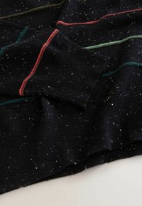 Pull en maille noir moucheté avec des rayures horizontales colorées et des poignets côtelés, présenté à plat sur une surface claire.