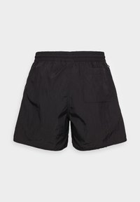 Shorts de sport noirs à texture rugueuse, taille élastique et une seule poche arrière. Pas de motifs ni d'ornements distincts.