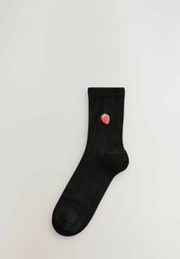 Svart bomullssocka med ribbad mudd och en liten broderad jordgubbsdesign på utsidan. Slät textur, i midjehöjd.