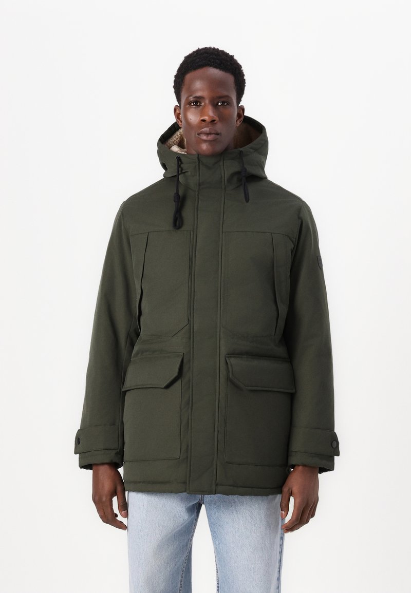 Parka de couleur vert foncé avec capuche, deux poches plaquées à l'avant et cordons de serrage réglables. Le tissu semble épais avec une légère texture.