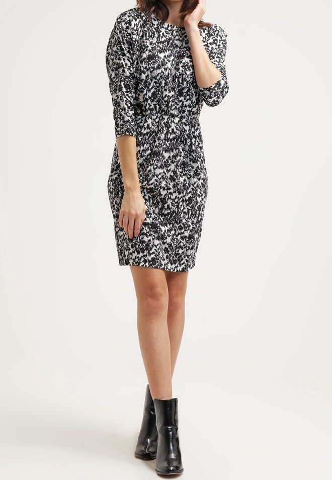 Sittande klänning i svart och vit abstrakt mönster, med trekvartslånga ärmar och draperad midja. Bärs med svarta ankelstövlar.