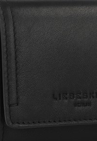 Cartera de cuero negro con una superficie texturizada, que presenta una solapa plegada y el nombre de la marca en relieve "LIEBESKIND BERLIN". Bordes cosidos.