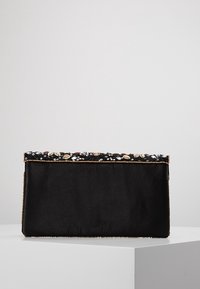Czarna kopertówka z satyny z ozdobnym obszyciem z koralików z metalicznymi i cekinowymi akcentami wzdłuż górnej krawędzi. Płaski, prostokątny kształt.