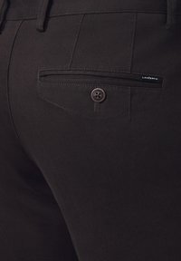 Czarne spodnie cechujące się teksturowanym materiałem, tylną kieszenią z okrągłym zapięciem na guzik oraz małą metką z logo.