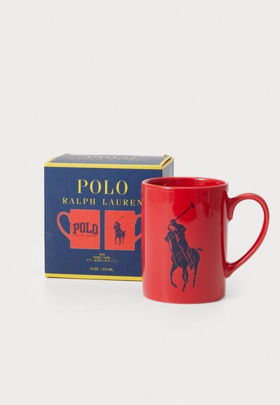 Sarkans keramisks krūze ar tumši zilu Polo logo un zirga vīrieti grafiku. Iekļauta zila un dzeltena kastīte ar uzrakstu "Polo Ralph Lauren." Tilpums 414 ml.
