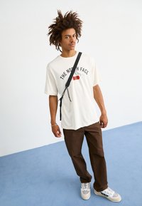 The North Face M VARSITY GRAPHIC RELAXED SS TEE - Triko s potiskem - white dune