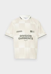 Cremefarvet kortærmet trøje med ternet mønster, der har sorte detaljer og logoer, herunder "DIVISION GARMENTS" på forsiden.