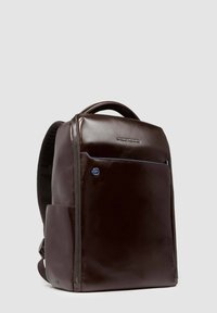 Zaino in pelle marrone scuro con finitura liscia, tasca frontale con zip, spallacci imbottiti e dettaglio del logo. Design elegante e moderno.