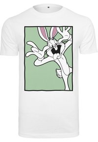 Maglietta bianca in cotone con grafica di un coniglio dei cartoni animati, orecchie rosa e sfondo verde, che mostra una posa animata e giocosa.