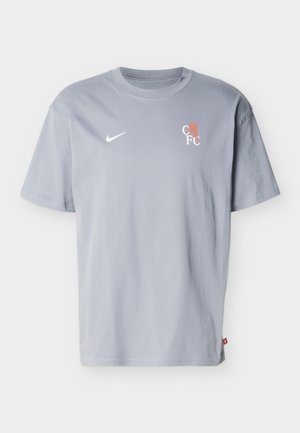 Svetlo siva majica kratkih rokavov Nike z okrolim izrezom, belim logotipom Nike Swoosh na levi strani prsnega koša in majhnim logotipom CF z oranžnim levom na desni strani prsnega koša.