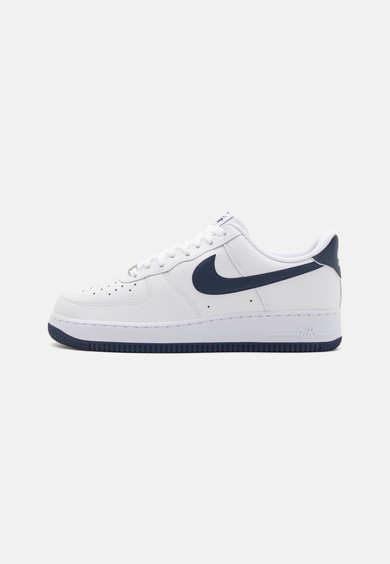 Baltas Nike Air Force 1 apavi ar tumši zilu swoosh, teksturētu ādas augšdaļu, baltām auklām un gumijas zoli ar tumši zilu rakstu.