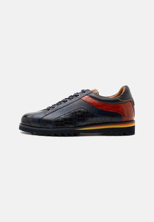 Sneaker in pelle bassa con texture coccodrillo nera, blu navy e rossa, chiusura frontale con lacci e suola nera scanalata con strisce gialle e rosse.