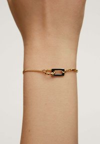Pulsera de oro con una delicada cadena y un cierre rectangular negro. El diseño es sencillo, con una textura y acabado elegantes.