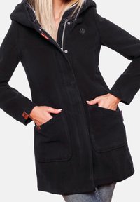 Giacca in pile nero con cappuccio, tasche anteriori, chiusura con cerniera e dettagli in pelle. Tessuto liscio e vestibilità comoda.