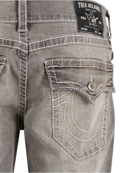 Jean en denim gris avec des coutures blanches contrastantes, un design de poche arrière unique et une étiquette de marque à la taille.