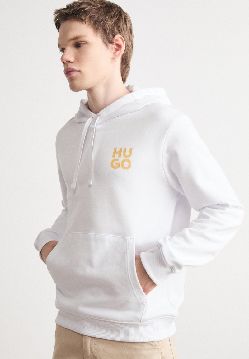Felpa bianca con tasca frontale a marsupio, coulisse regolabile e logo giallo "HUGO". Tessuto liscio, orlo e polsini a coste.