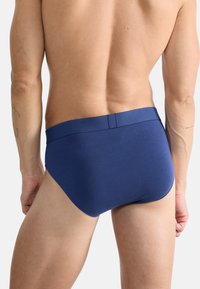 Caleçons pour hommes bleu marine en tissu lisse, dotés d'une taille haute et d'un design ajusté. Construction simple et sans coutures.