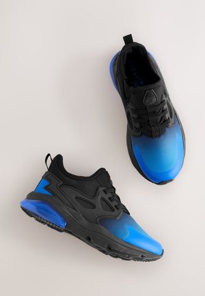 Chaussures de sport noires et bleues avec une tige lisse en dégradé, des superpositions texturées et une semelle translucide bleue. Elles comportent une fermeture à lacets et une languette au talon.