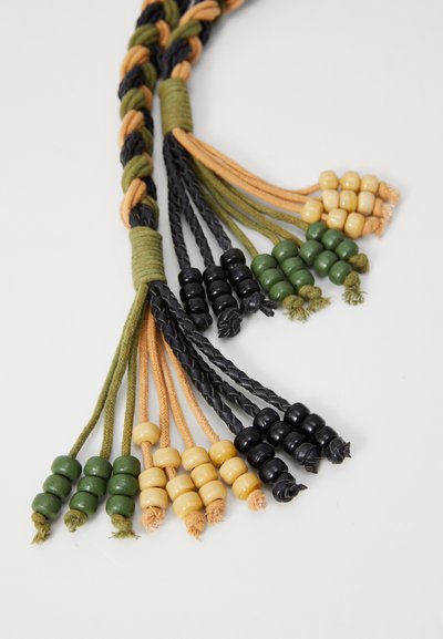 Accessoire textile tressé avec des cordons verts, noirs et marron. Accents en perles de différentes couleurs aux extrémités, avec des surfaces lisses et texturées.